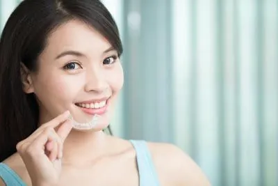 woman holding her clear aligners from Acre Wood Dental - Waco