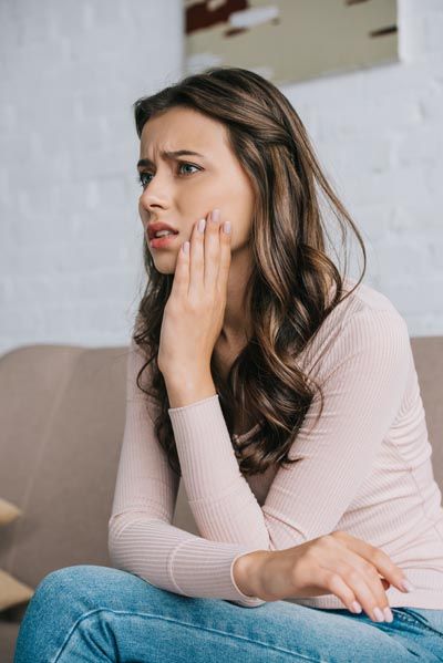 woman holding her mouth from tooth pain